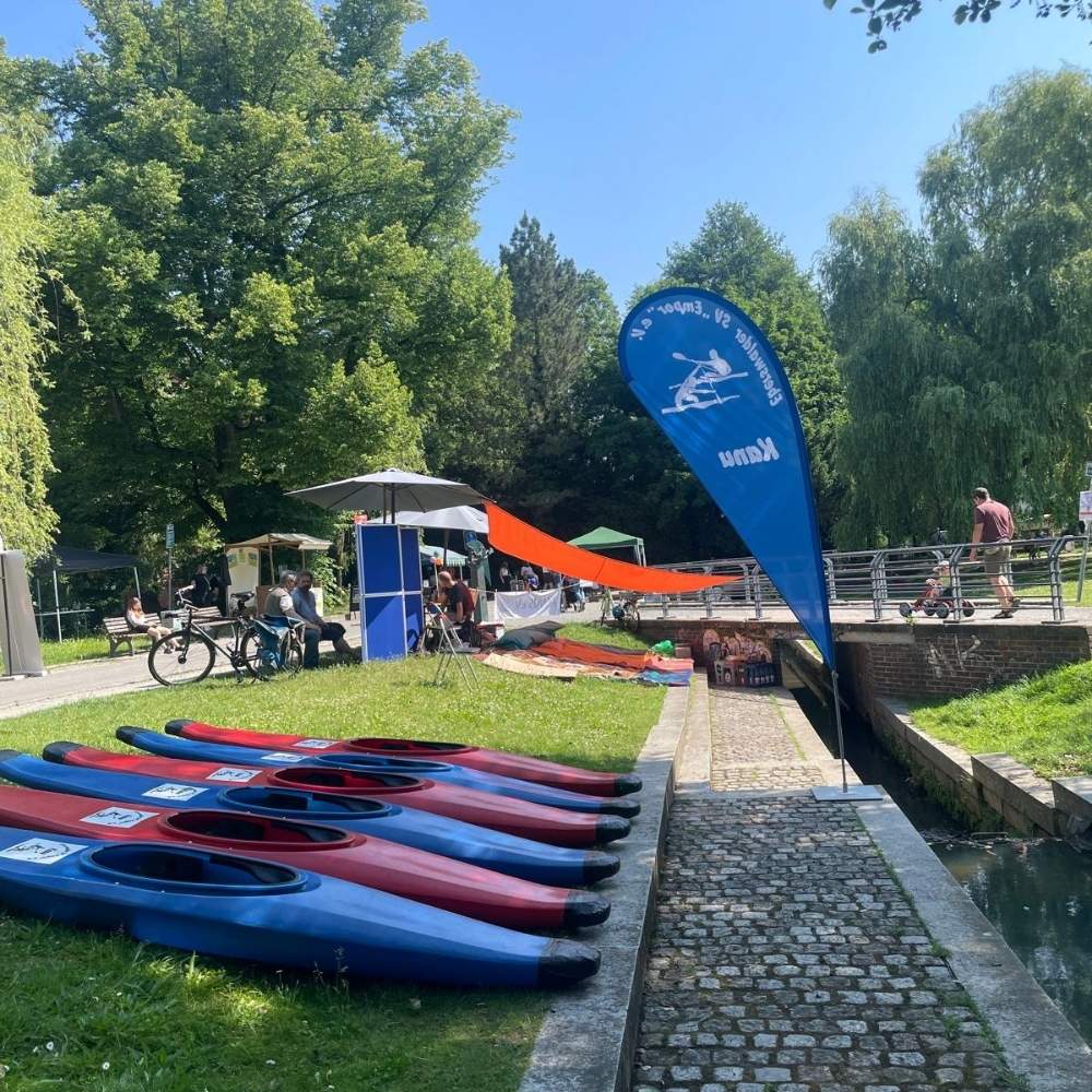 mehrere kanus liegen außerhalb des wassers, menschen sind im hintergrund zu sehen